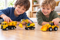 Dos niños jugando con tres vehículos de construcción de juguete